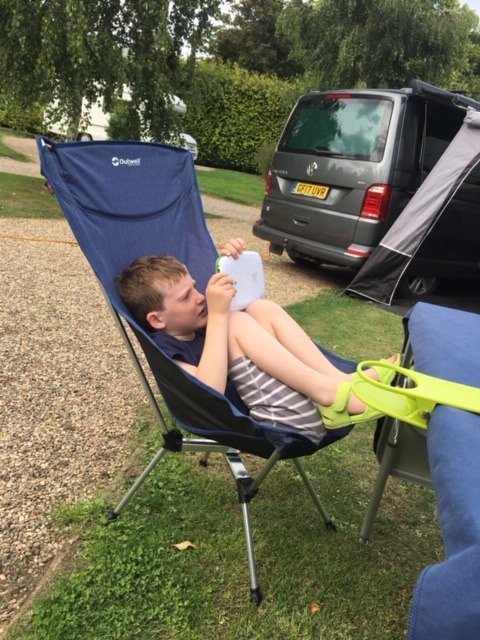 Reading on a camp chair next to the campervan
